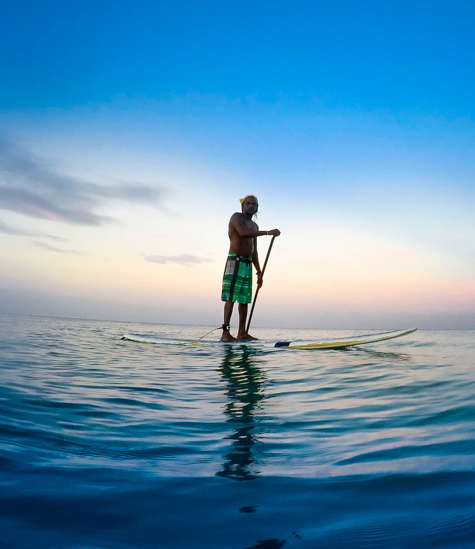 A boy doing stand up paddle boarding in calm water